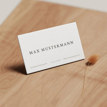 Elegante Visitenkarten Vorlage in Weiß mit minimalistischer Gestaltung auf Holzoberfläche für Canva, Louvion.de