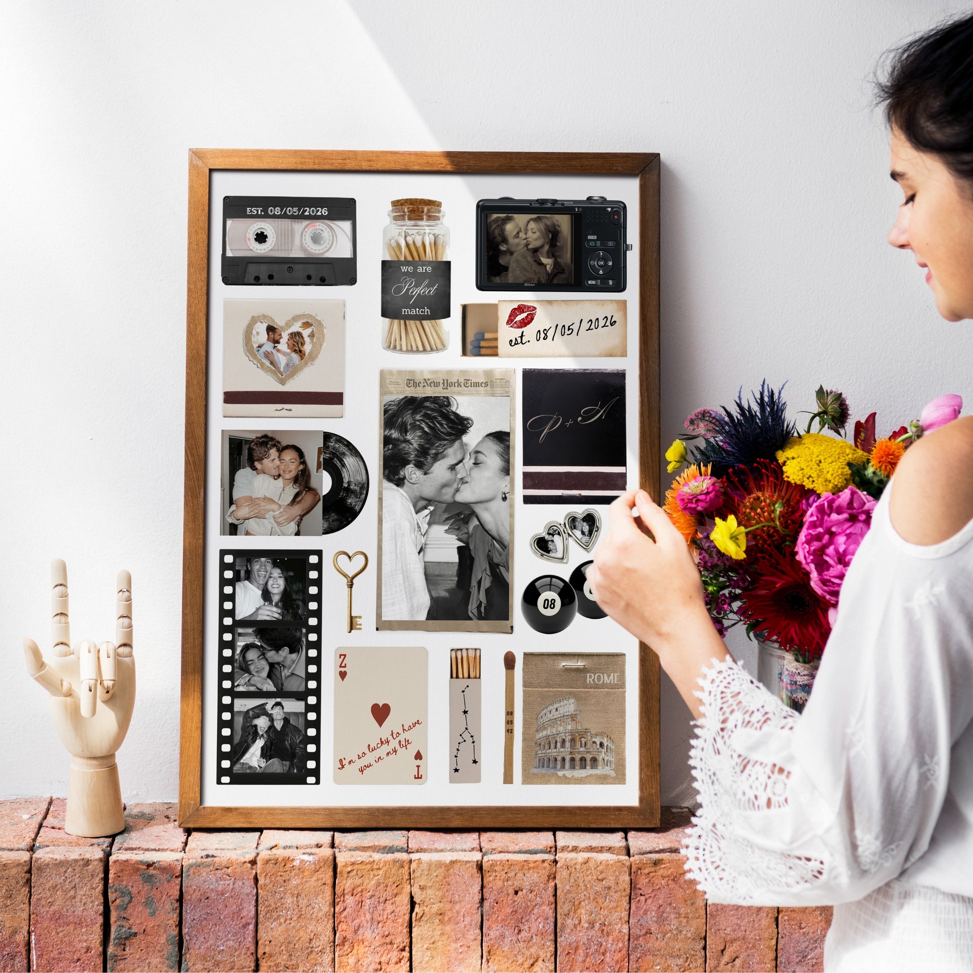 Personalisiertes Matchbook Poster in einem Holzrahmen, platziert auf einem Backsteinsims neben einer Frau mit Blumenstrauß.