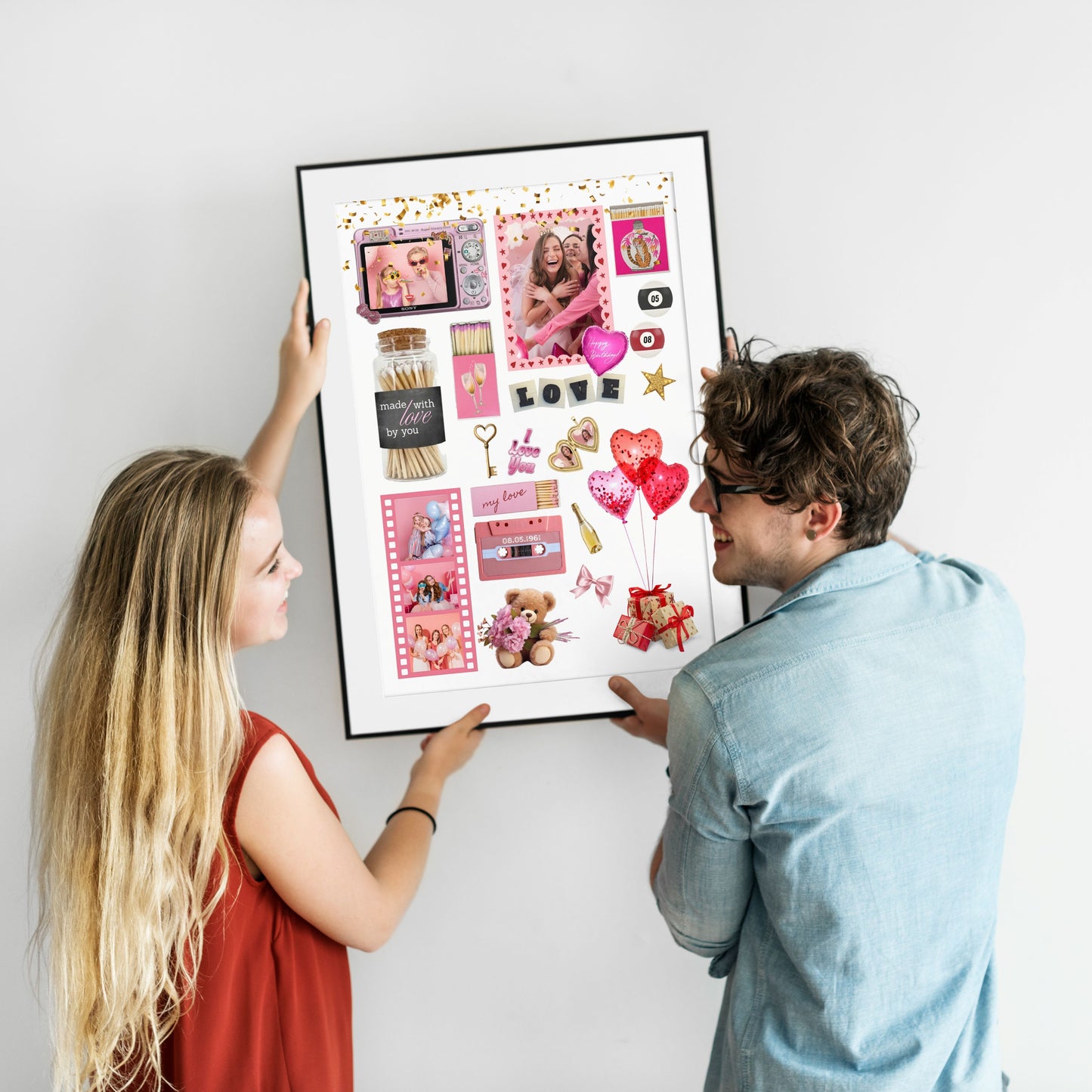 Ein lächelndes Paar hängt ein gerahmtes, personalisiertes Matchbook Poster mit gemeinsamen Fotos als Wanddeko an eine weiße Wand.