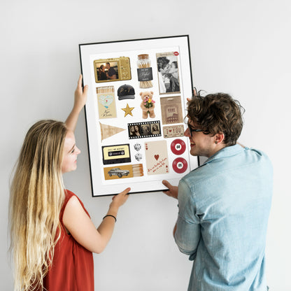 Glückliches Paar hängt ein gerahmtes, personalisiertes Matchbook-Poster mit eigenen Fotos als moderne Wanddeko auf.