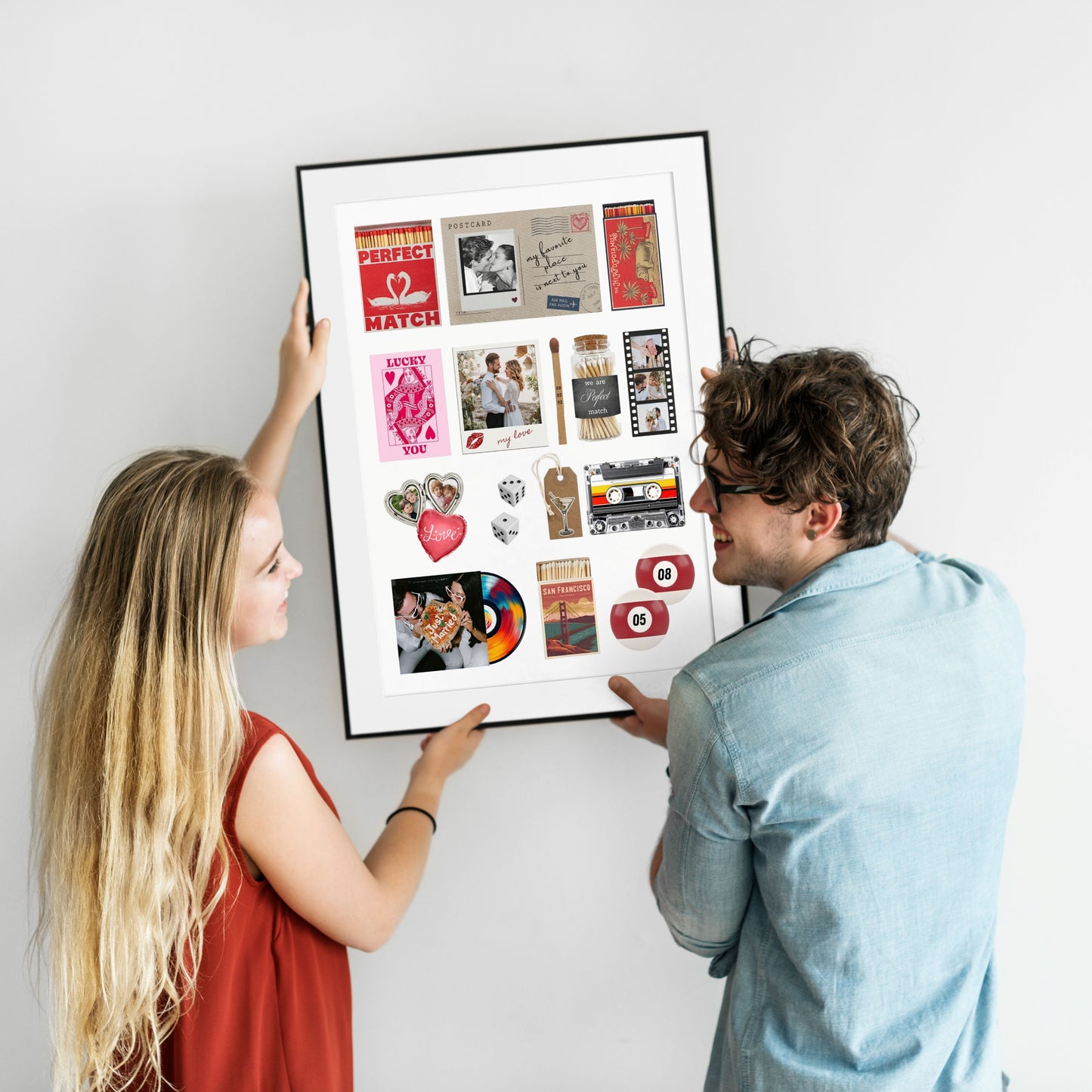 Ein lächelndes Paar hängt ein großes, gerahmtes Matchbook-Poster mit persönlichen Fotos als individuelle Wanddeko auf.