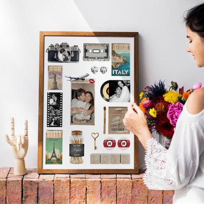 Personalisiertes Matchbook Poster in einem Holzrahmen auf einer Ziegelwand neben einer Frau mit Blumenstrauß.