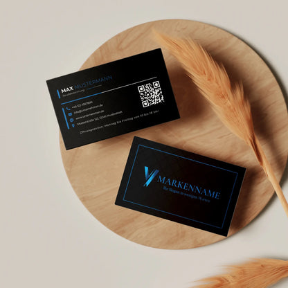 Professionelle Visitenkarten Vorlage in Schwarz und Blau mit Vorder- und Rückseite, Logo sowie QR-Code auf stilvoller Holzplatte präsentiert | Louvion.de