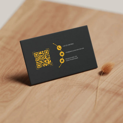 Realistische Vorschau der schwarz-gelben Visitenkarten Vorlage mit QR-Code und Kontaktdaten auf Holzoberfläche – Louvion.de